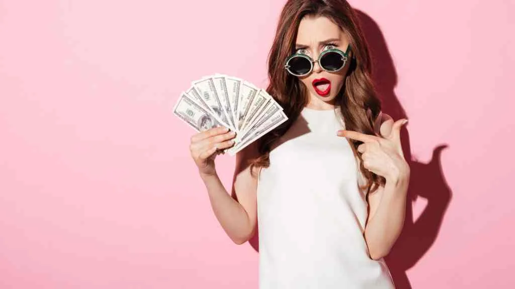 woman holding money while wearing sunglasses